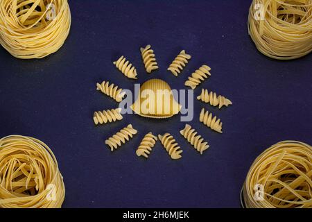 Advertising of different pasta diagonally Mixed pasta, spaghetti, horns, spirals and shells on a blue background for advertising menu. Stock Photo