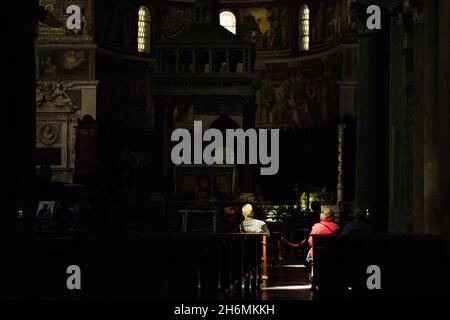 Dark church and people praying under the sunlgiht Stock Photo