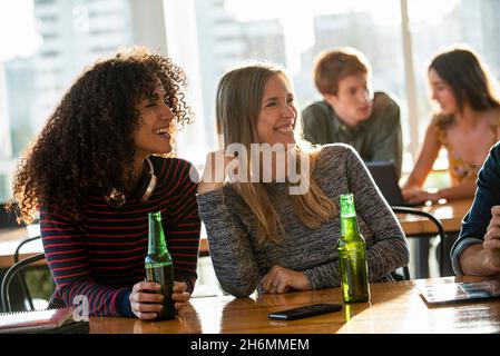 Smiling women looking away while sitting in office Stock Photo