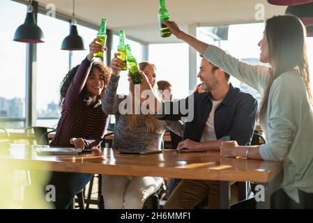 Smiling colleagues toasting drink bottles in office Stock Photo