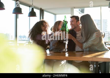 Smiling colleagues toasting drink bottles in office Stock Photo