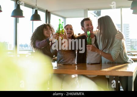 Smiling colleagues toasting drink bottles in office Stock Photo