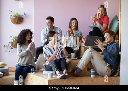 Business people clapping hands and celebrating in office Stock Photo