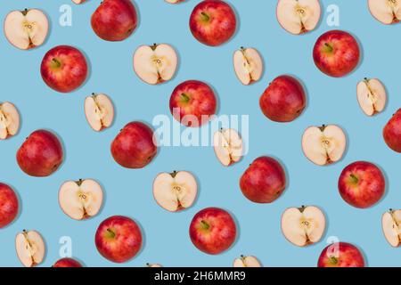 Trendy pattern of fresh whole apple and halves on  pastel blue background. Minimalist isometric food concept.  Flat lay Stock Photo