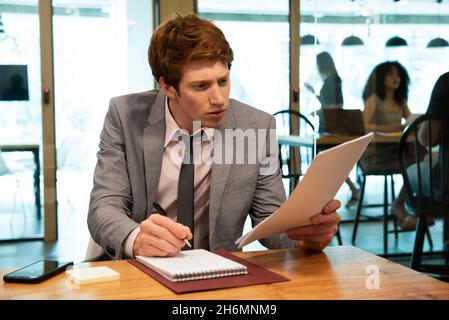 Young businessman writing on notebook in office Stock Photo