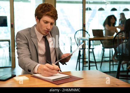 Young businessman writing on notebook in office Stock Photo