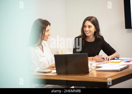 Businesswomen talking with each other in office Stock Photo
