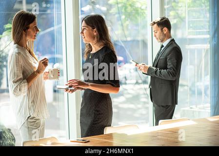Businesswomen talking with each other in office Stock Photo
