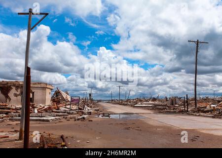 View of dirt road passing through abandoned village against cloudy sky, Villa Epecuen Stock Photo