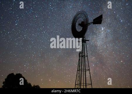 View of aermotor windmill spinning against milky way in sky Stock Photo