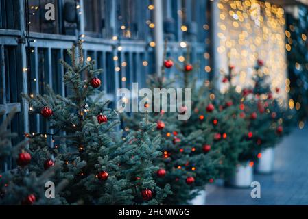 Christmas tree decorated with toys, against background of window with burning garland Beautiful luxurious Christmas tree with red balls,cone close-up Stock Photo