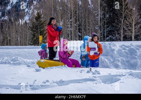 One adult and four children in the snow look off camera, watching racers at the Chama Chile Ski Classic. Stock Photo