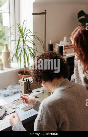 Vertical shot of two tailors sewing together at a workshop Stock Photo
