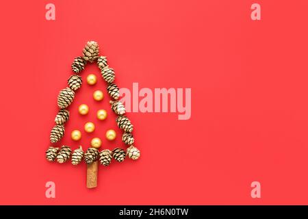 Greeting card. Christmas tree from golden cones on a bright red background. Top view, copy space for text. Minimal Christmas concept Stock Photo