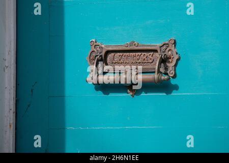 A vintage through the door mail slot and door knocker. The antique brass metal is distressed and embossed with stamped word letters. Stock Photo
