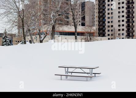 Empty picnic table at a snow-covered playground in a residential area of Longueuil, Quebec, Canada Stock Photo