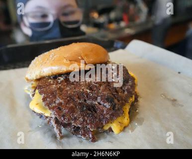 St. Louis, United States. 16th Nov, 2021. Manager Hailey Mattof delivers a plain double cheeseburger to a customer in the dining room at the Hi-Pointe Drive In, in St. Louis on Tuesday, November 16, 2021. The World Food Championships held in Dallas on November 10th, crowned the Hi-Pointe Smash Burger the best burger in the United States. Chefs in the category were challenged to create a burger using Impossible vegetarian meat. Hi-Pointe owner and chef Mike Johnson said he made his famous Cowboy Burger for the competition. Photo by Bill Greenblatt/UPI Credit: UPI/Alamy Live News Stock Photo