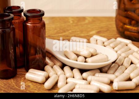 Herbal eco dietary supplements pills in the spoon on the wooden table. Healthy eating and medicine Stock Photo