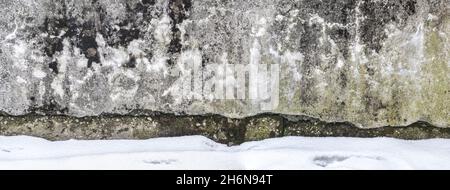 weathered and damaged concrete wall near foundation. winter time. panoramic view. Stock Photo