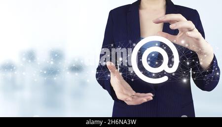 Email marketing concept. Sending newsletter. Two hand holding virtual holographic Email and sms icon with light blurred background. Business email con Stock Photo