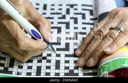 Generic image of  female elderly hands using a pen to fill in a crossword puzzle. Stock Photo