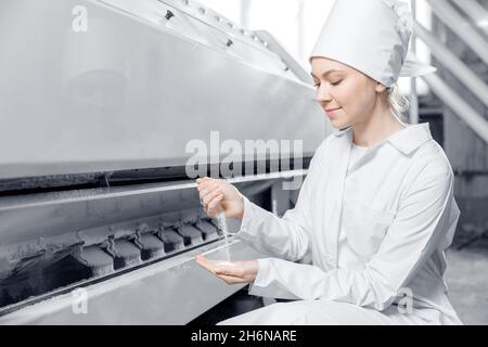 Woman operator checks quality of finished food products. Modern electrical mill machinery for production of wheat flour. Stock Photo