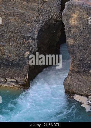 Close-up view of raging stream Kicking Horse River flowing through narrow gap between eroded rocks at Natural Bridge in Yoho National Park, Canada. Stock Photo