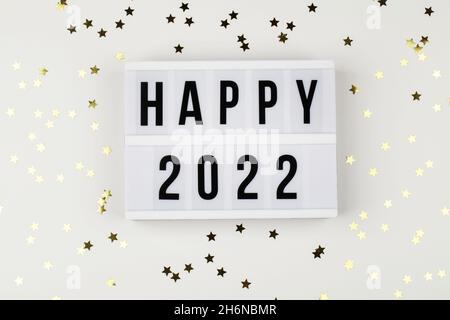 lightbox with words happy 2022 and holiday confetti on white background. top view new year celebration. party background. Stock Photo