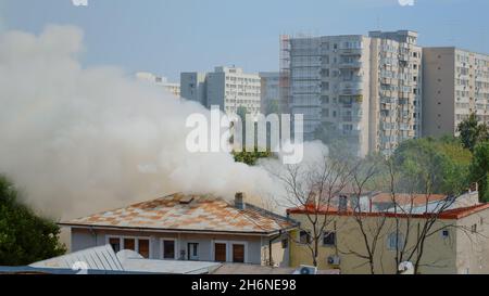 View of firefighters using water to extinguish fire from burning house ...