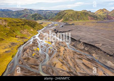 River with fanned out branches through black lava sand, mountain landscape overgrown with moss, Hoefoabrekkajoekull glacier in the background Stock Photo