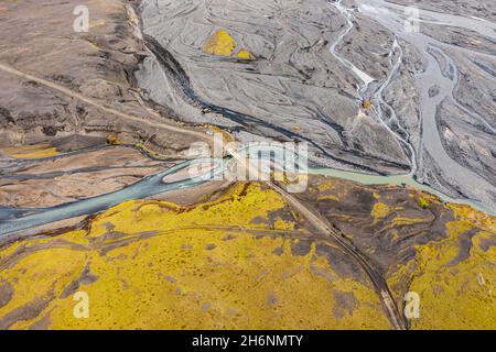 Road over river, river with fanned out branches through black lava sand, landscape overgrown with moss Icelandic highlands, view from above, aerial Stock Photo