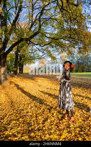 Portrait of a smiling, dark-skinned woman with curls in a dress, outdoor shot in autumn, Germany Stock Photo