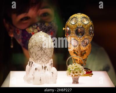 A museum employee looks at a display case containing the Winter Egg (foreground) and the Romanov Tercentenary Egg (background)during a photo call for the Victoria and Albert Museum's forthcoming exhibition 'Faberge in London: Romance to Revolution'. Picture date: Wednesday November 17, 2021. Stock Photo