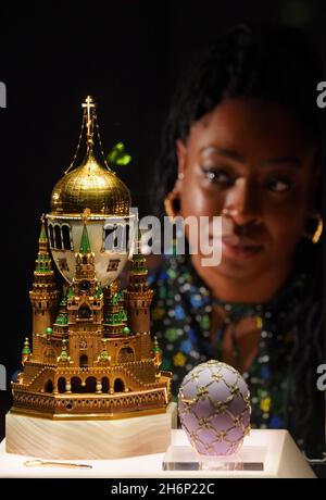 A museum employee looks at a display case containing the Moscow Kremlin Egg (left) and the Swan Egg (right) during a photo call for the Victoria and Albert Museum's forthcoming exhibition 'Faberge in London: Romance to Revolution'. Picture date: Wednesday November 17, 2021. Stock Photo