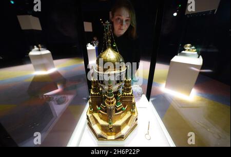 A museum employee looks at a display case containing the Moscow Kremlin Egg (centre) and the Swan Egg (right) during a photo call for the Victoria and Albert Museum's forthcoming exhibition 'Faberge in London: Romance to Revolution'. Picture date: Wednesday November 17, 2021. Stock Photo