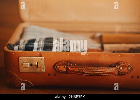 In an open orange old retro suitcase there are clothes and various things. Tourist's luggage for the trip. Household items of the 20th century. Custom Stock Photo