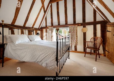 Stoke By Clare, England October 17 2019: Bedroom interior inside traditional english cottage with exposed beams, bed and sloping ceiling Stock Photo