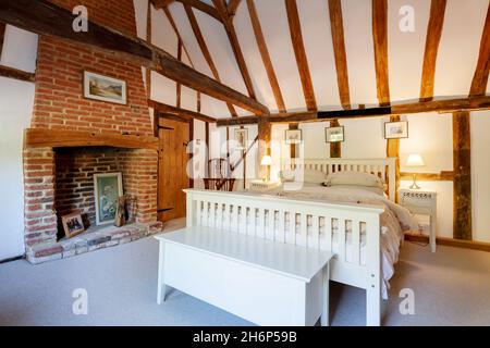 Stoke By Clare, England October 17 2019: Bedroom interior inside traditional english cottage with exposed brickwork and beams, inglenook fireplace and Stock Photo
