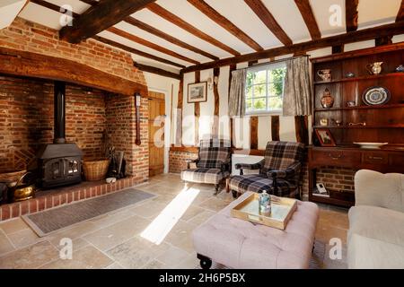 Stoke By Clare, England October 17 2019: Living room interior inside traditional english cottage with exposed brickwork and beams, inglenook fireplace Stock Photo