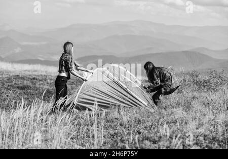 Girls set up tent on top mountain. Camping skills concept. Camping and hiking. In middle of nowhere. Temporary housing. Vacation in mountains. Camping Stock Photo