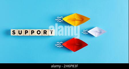 Two paper boats support the small boat. Assistance, consultancy, aid or support service in business or technology concept. Stock Photo