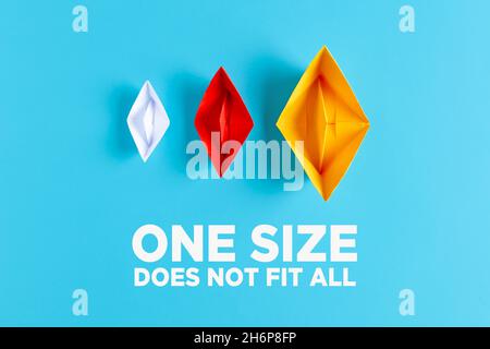 Difference, variety, plurality or diversity concept. Three paper boats with different size and colors on blue background with the text one size does n Stock Photo