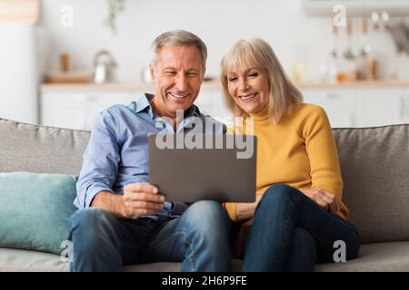 Happy Mature Couple Using Laptop Browsing Internet Together At Home Stock Photo