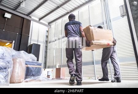 Men delivering boxes from a truck. Furniture delivery. Stock Photo