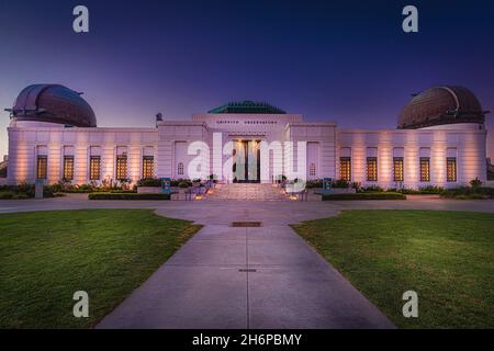 Los Angeles, CA—Nov 14, 2021; view of front of Griffith Observatory illuminated at sunrise showing copper domes and door of the California landmark in Stock Photo