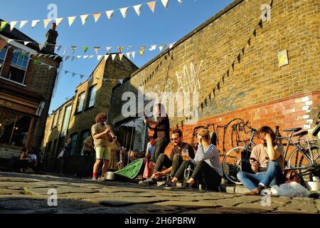 London, Great Britain - May 20, 2018 : Young people having fun drinking  and listening to street musicians in Hackney, East London on a sunny day Stock Photo