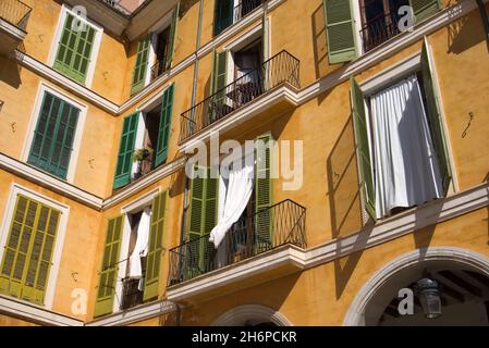Balconies and windows in different green hues at an orange facade of mediterranean house Stock Photo