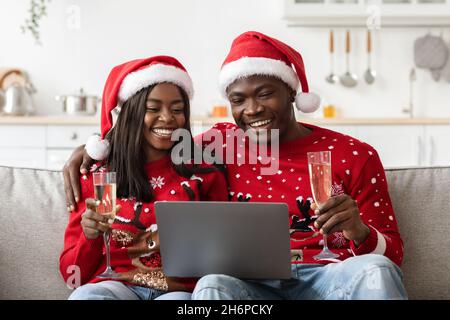 Happy black couple having online New Year party, using laptop Stock Photo