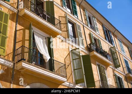 Balconies and windows in different green hues at an orange facade of mediterranean house Stock Photo