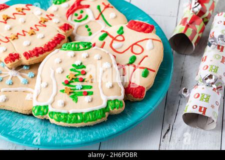 A plate of ugly Christmas sweater cookies with festive crackers to the right. Stock Photo